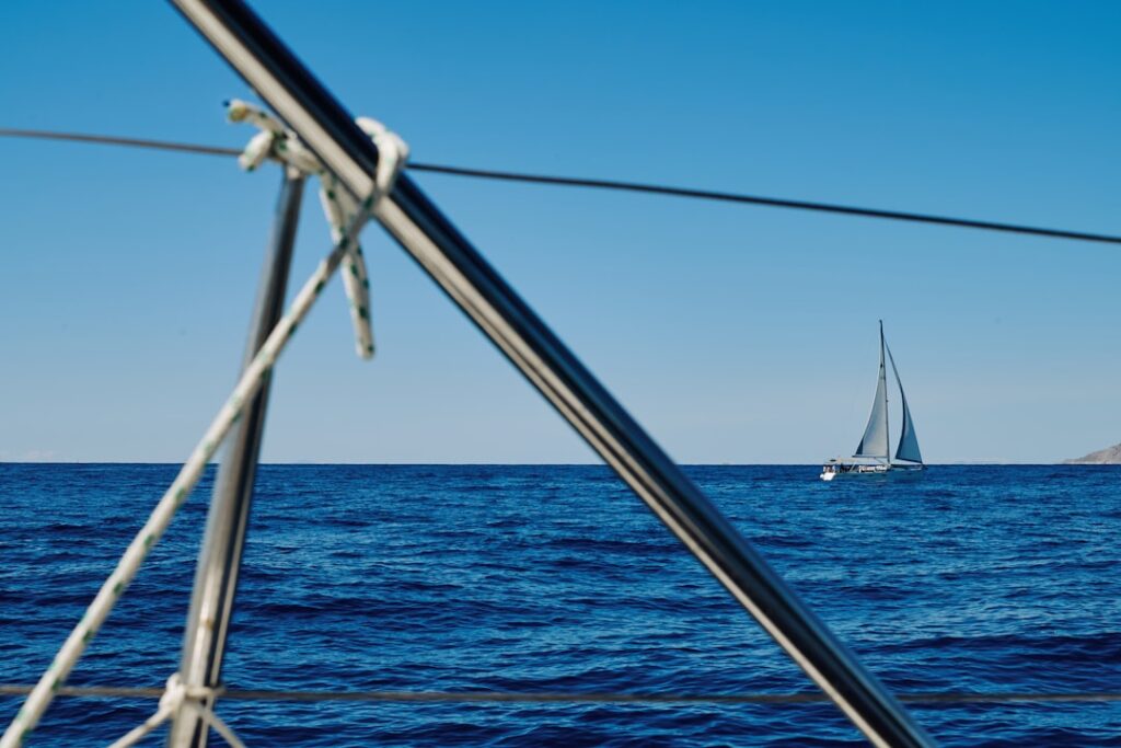 A distant sailboat glides on the ocean.