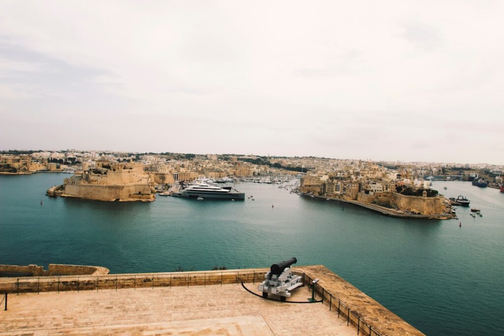 Historic coastal city with a large yacht in harbor.