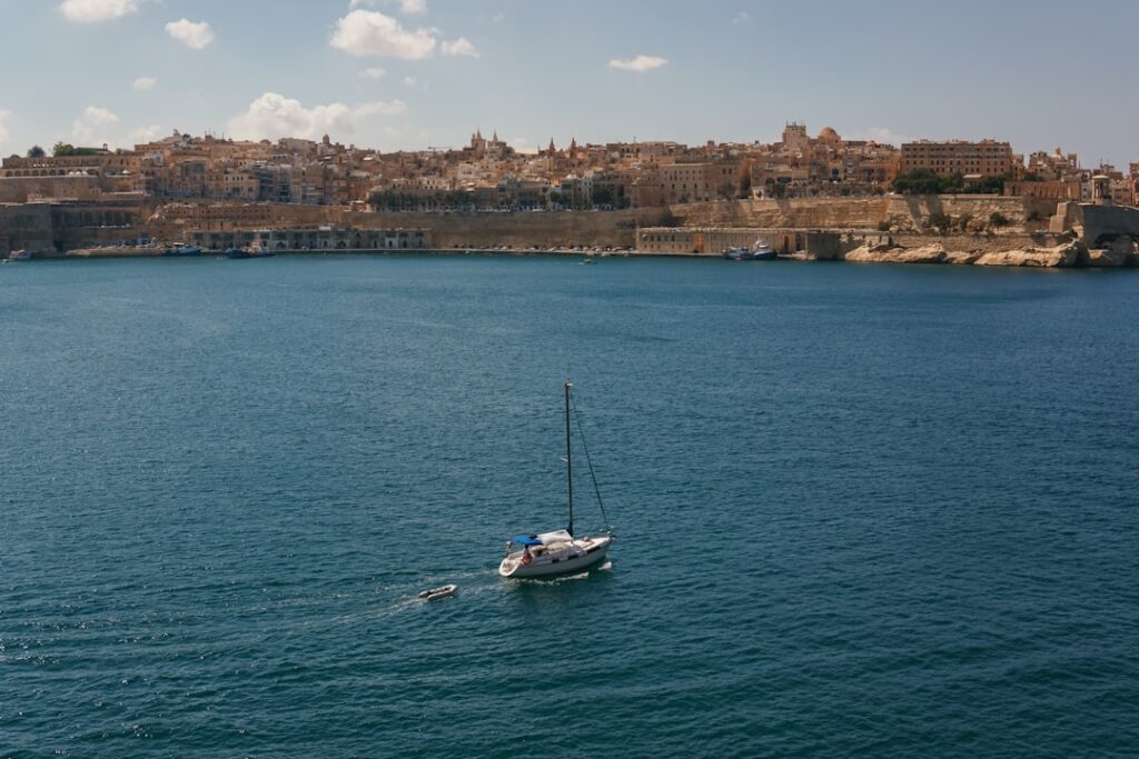 A sailboat in a body of water with a city in the background